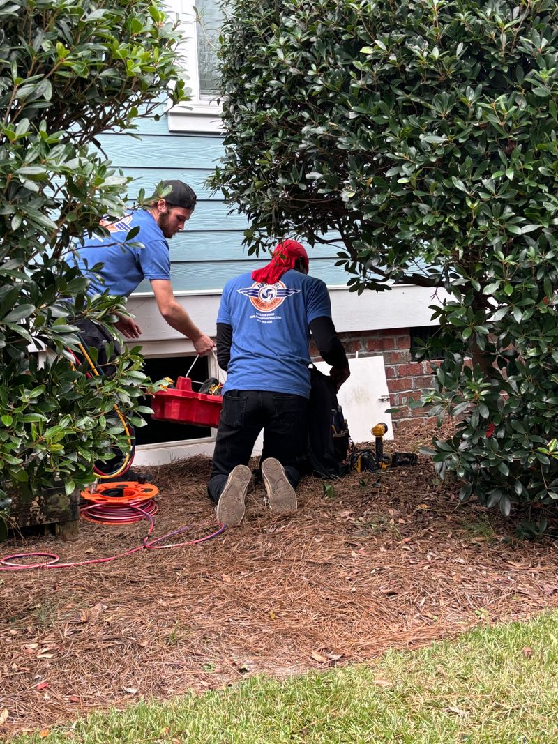 Two Air Support technicians servicing an outdoor HVAC unit at a Wilmington area home