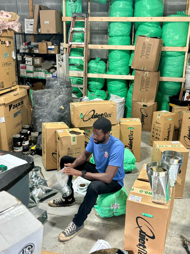 Air Support team member preparing duct components with Daikin and Quietflex inventory in background