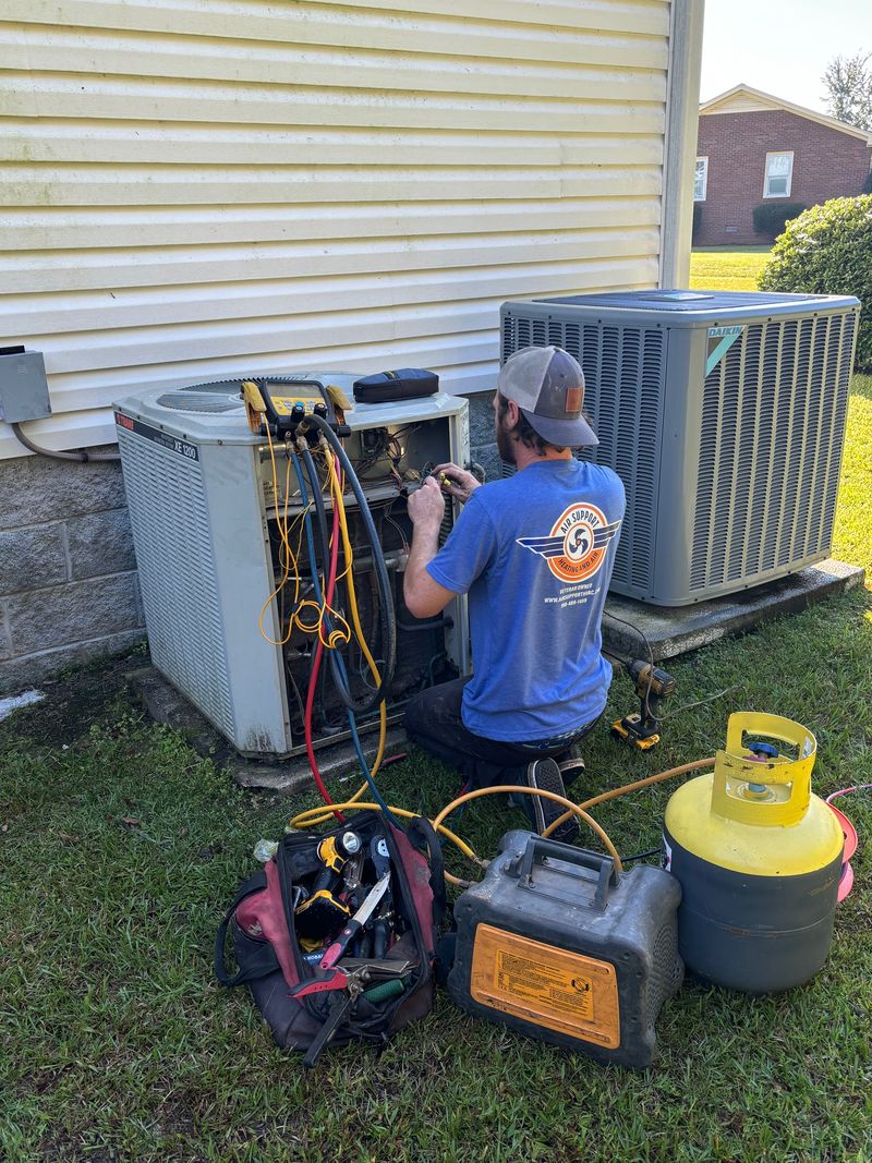Air Support technician checking refrigerant levels on a residential AC condenser with manifold gauges