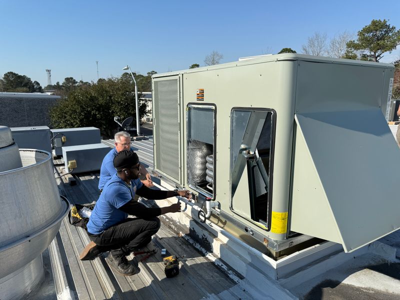 Two Air Support technicians servicing a commercial rooftop package unit