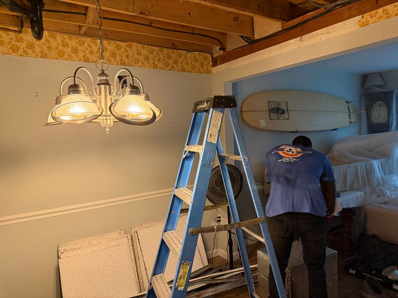 Air Support technician on ladder performing ceiling ductwork repair in a coastal NC home