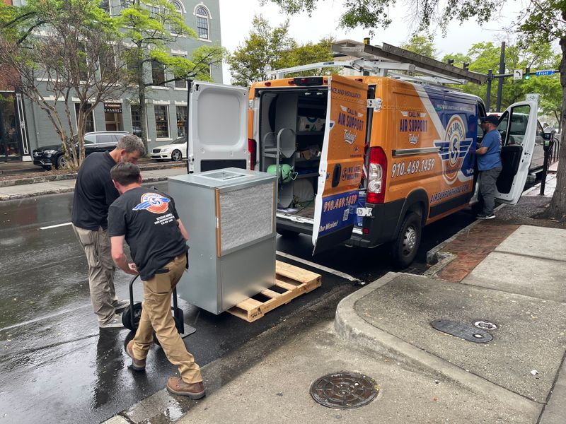 Air Support technicians unloading an air handler from branded van in downtown Wilmington