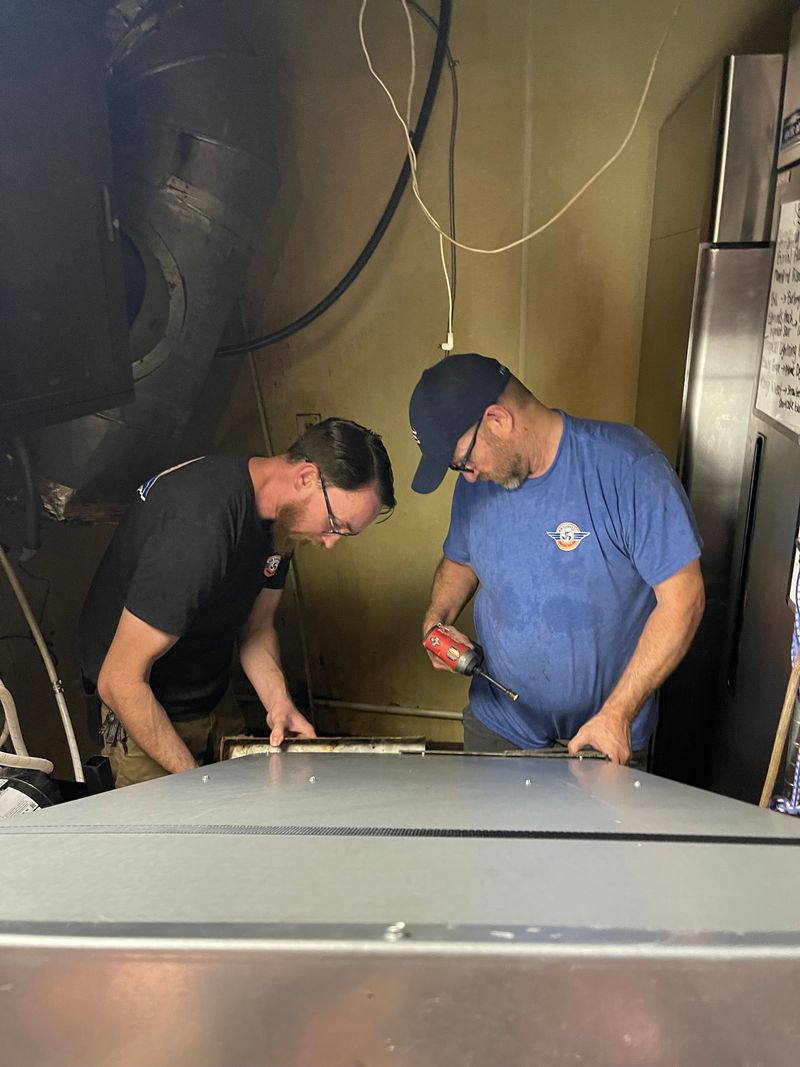 Two Air Support technicians working on commercial ductwork and air handler connections
