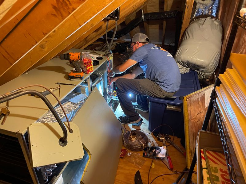 Air Support technician servicing an air handler unit in a residential attic space