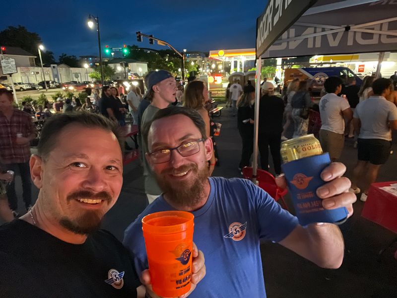 Air Support team members networking at a Wilmington community event with branded koozies