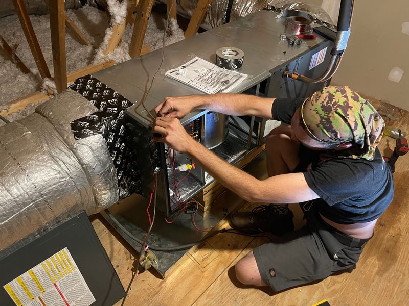 Air Support technician wiring an evaporator coil on an air handler in an attic space