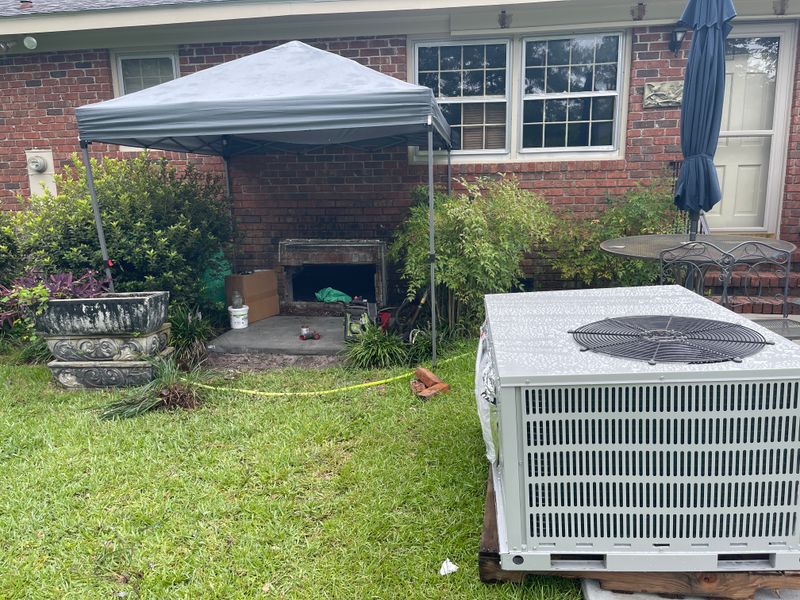New AC condenser unit staged for installation at a Wilmington area brick home with canopy tent