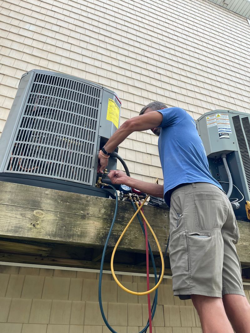 Air Support technician connecting refrigerant lines on elevated deck-mounted condenser units