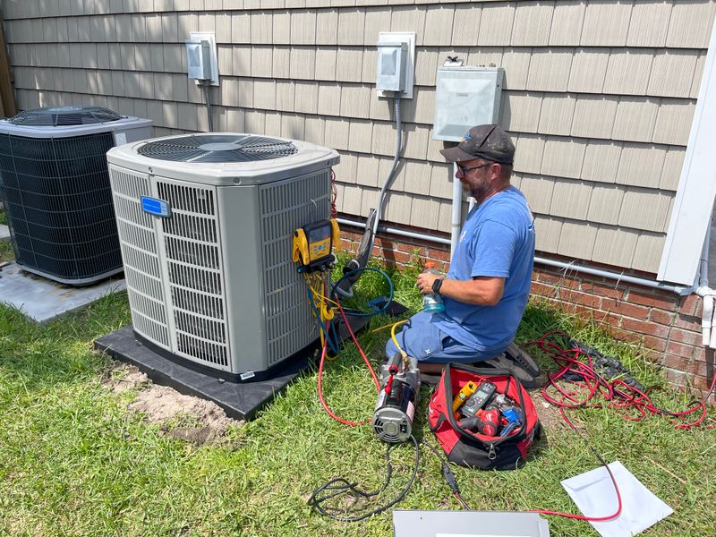 Two Air Support technicians servicing American Standard outdoor condenser units at a residential home