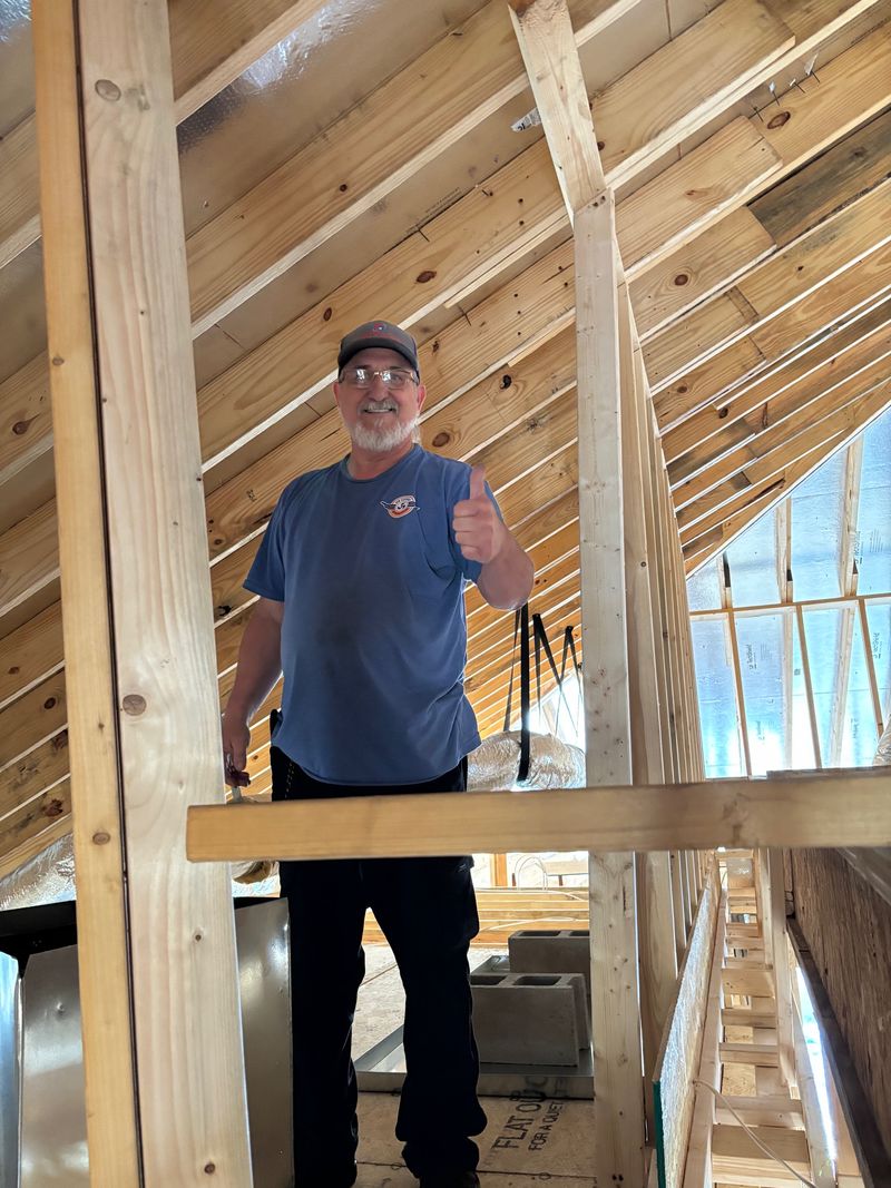 Air Support technician standing in new construction wood framing during HVAC rough-in