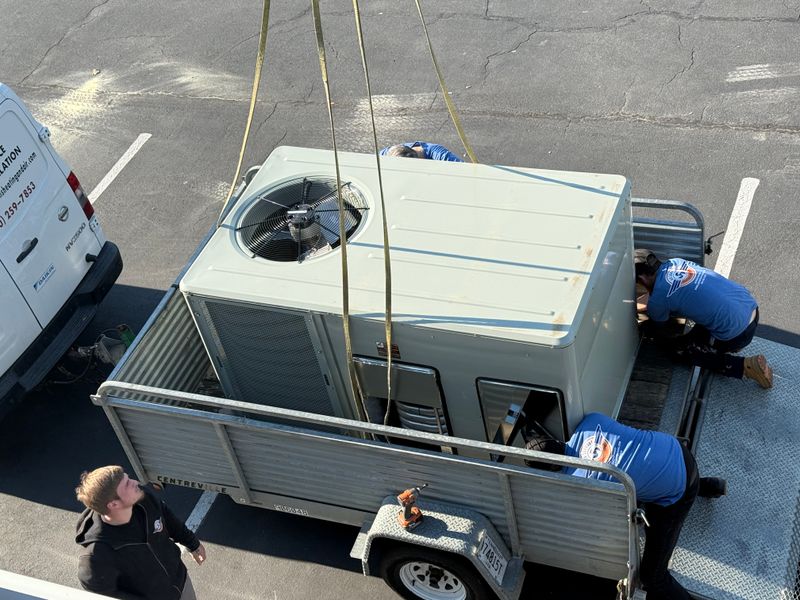 Air Support team preparing a large commercial HVAC rooftop unit for crane lift onto trailer