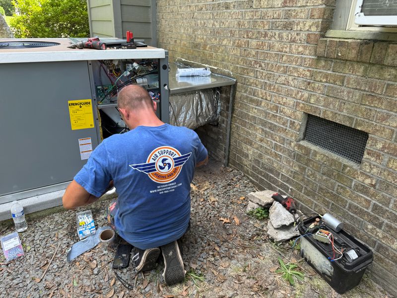 Air Support technician servicing a heat pump package unit with EnergyGuide label visible